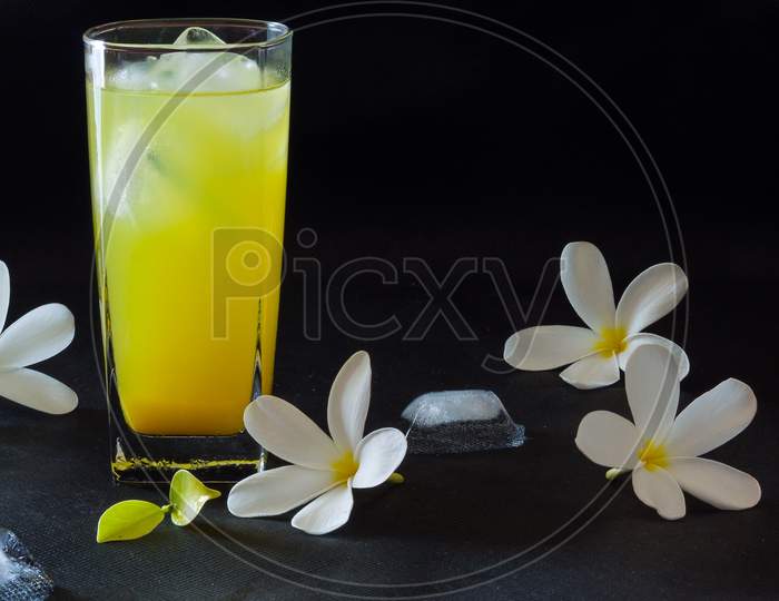 Glass of  fresh,sweet orange juice with frangipani flowers,isolated on black background.
