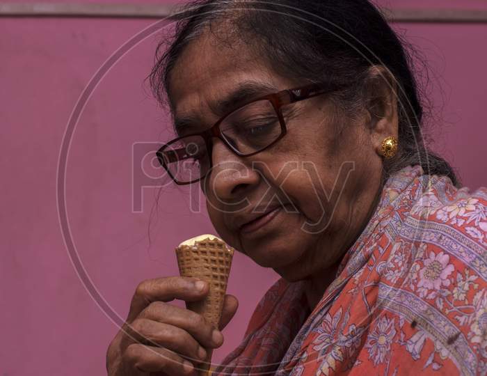 An Old Lady Enjoying Cone Ice Cream. Selective Focus.