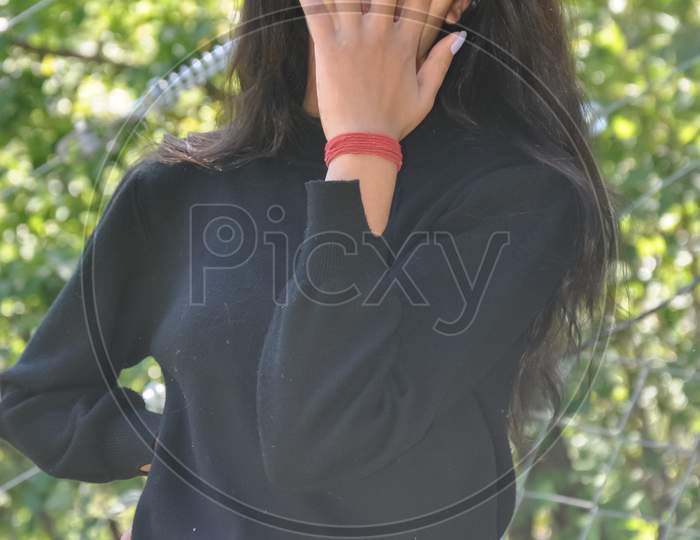 Portrait of a young girl with casual clothing posing outdoor in nature with covering her face with hand