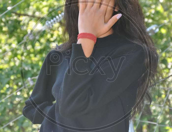 Portrait of a young girl with casual clothing posing outdoor in nature with covering her face with hand