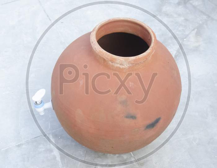 Selective focus on CLAY PITCHER WITH PLASTIC TAP. Handmade indian craft. Village life.