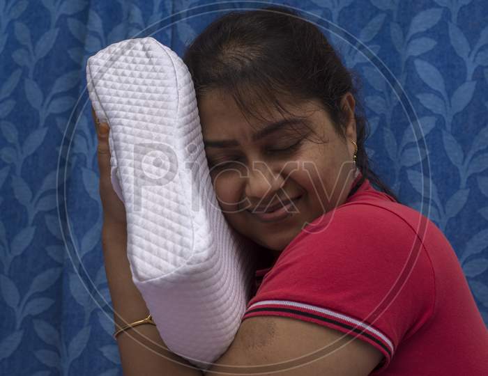 A Female Hand Testing Softness Of A Orthopedic Memory Foam Pillow For Comfort.