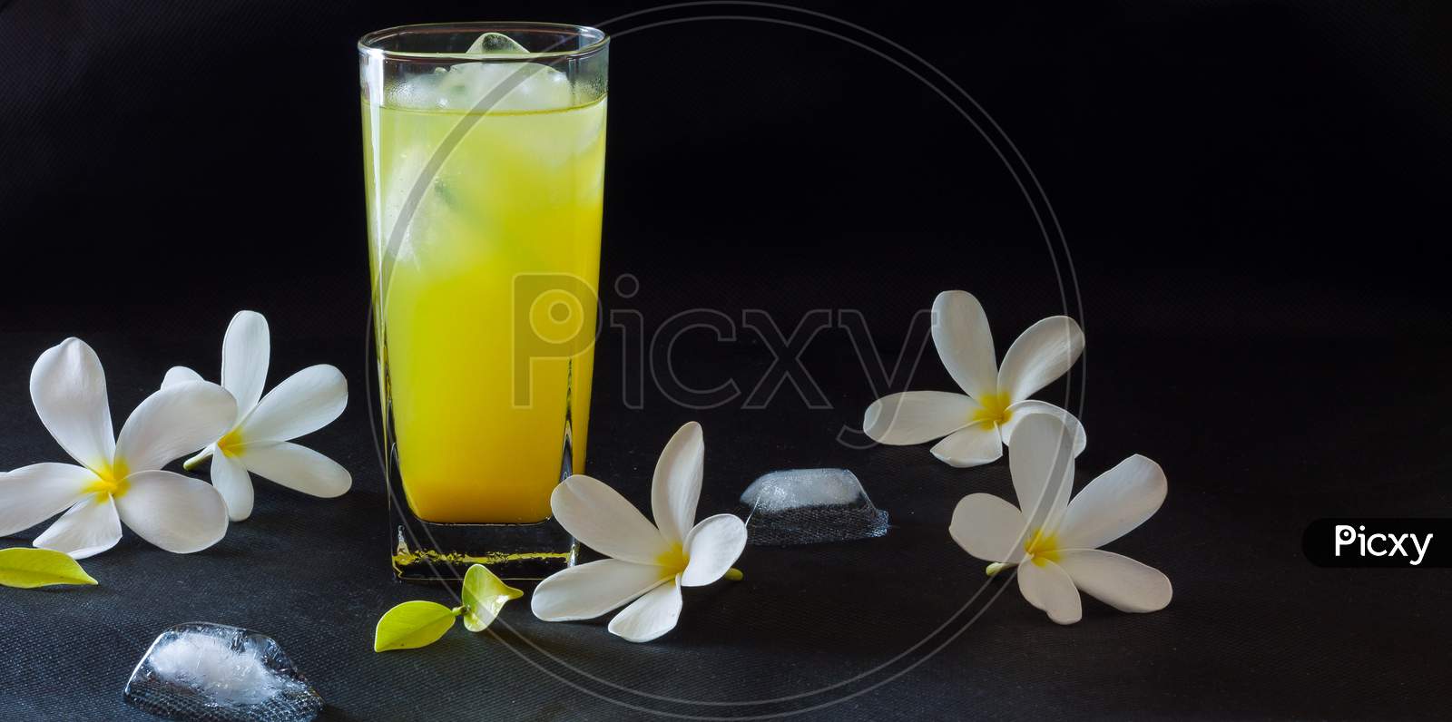 Glass of  fresh,sweet orange juice with frangipani flowers,isolated on black background.