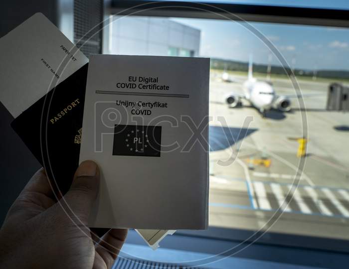 Covid-19 Coronavirus Pandemic And Travel Concept, Covid Vaccination Passport Along With Boarding Pass Against Out Of Focus Flight At Airport. New Normal Way Of Traveling After Covid Pandemic