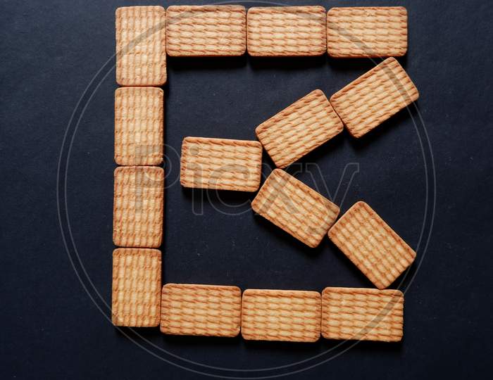 Glucose Biscuits placed in B shape on shape on black texture