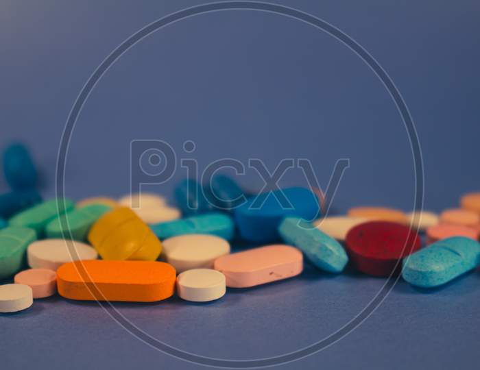 Numerous Colored Pills On A Neutral Blue Background. Free Space To Write.