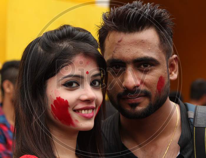 A young indian bengali couple dressed in red and black ethnic indian dress and smiling