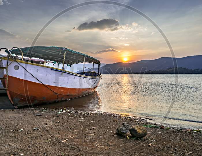 Beautiful Sunset Behind A Parked Red And White Boat At Shore In Bamnoli, Maharashtra,India.