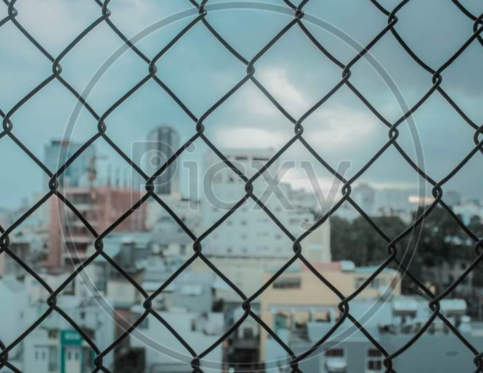 A Close-Up Of The Fence From Steel Mesh With Cityscape'S Background In Ho Chi Minh City, Vietnam