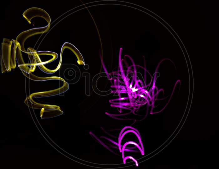 Unique, long exposure, color Led light painting photograph of abstract pattern on black background.
