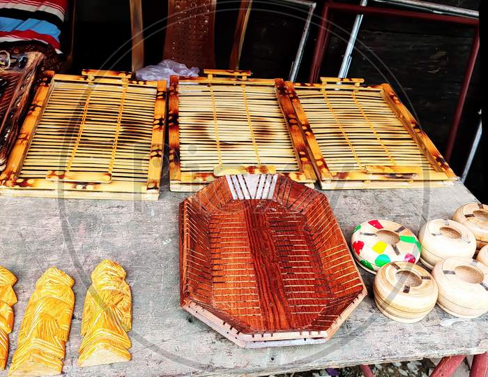Handmade wooden trays, ashtrays and dolls being displayed on the table during handcraft festival in Kolkata, India. Selective focus on subjects.