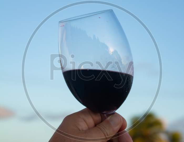 Crystal Glass Containing Red Wine Raised Towards The Sky In An Attitude Of Tasting Or Celebration.