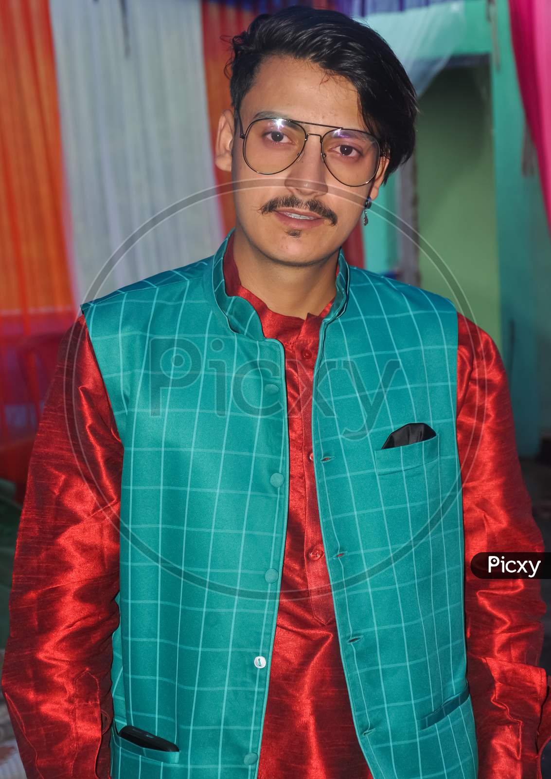 Portrait of a handsome Indian young guy with wearing kurta, pajama, nehru coat and sunglasses with looking at camera