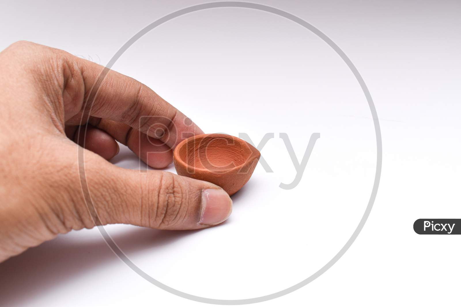Placing Diya Or Clay Oil Lamp With Fingers For Diwali Festival Of Lights With White Background