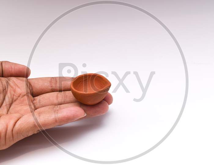 Holding Handmade Diya Or Clay Oil Lamp With Fingers Used For Diwali Festival Of Lights With White Background