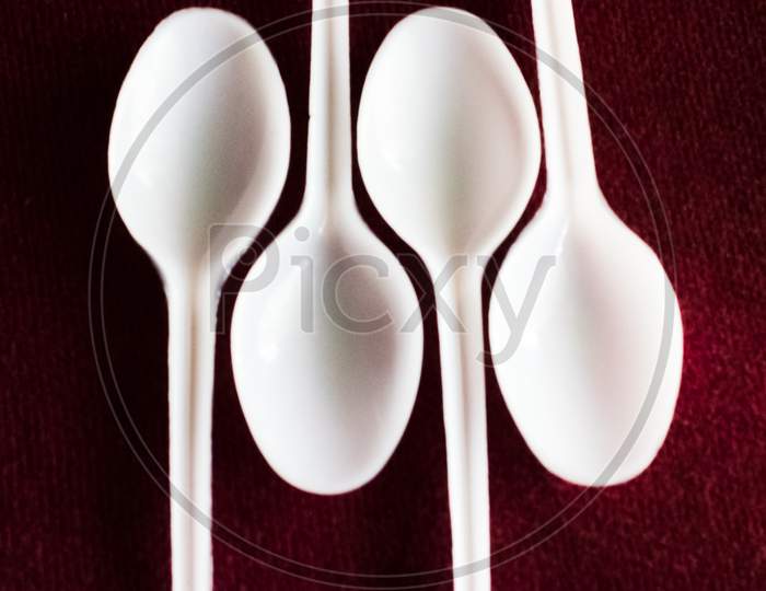 Some Empty Plastic Spoon In A Red Carpet