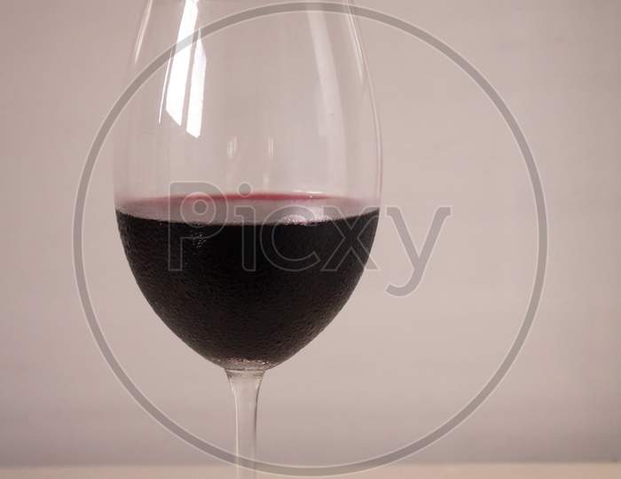 Crystal Goblet Containing Red Wine On A Neutral White Background. Available Space To Write.