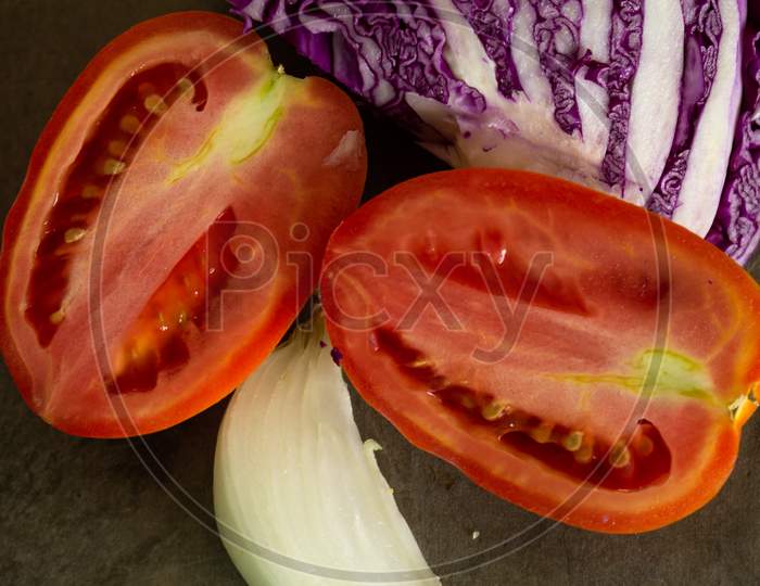 Tomatoes And Red Cabbage Cut On A Table. Ingredients For A Vegan Salad.
