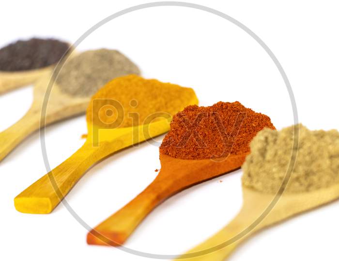 Indian Curry Powders In Wooden Spoon. White Background. Selective Focus