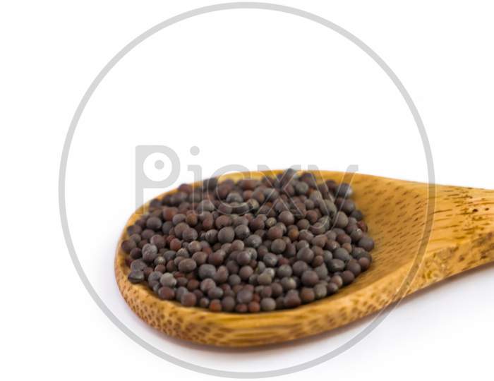 Black Mustard Seeds In Wooden Spoon. White Background. Selective Focus