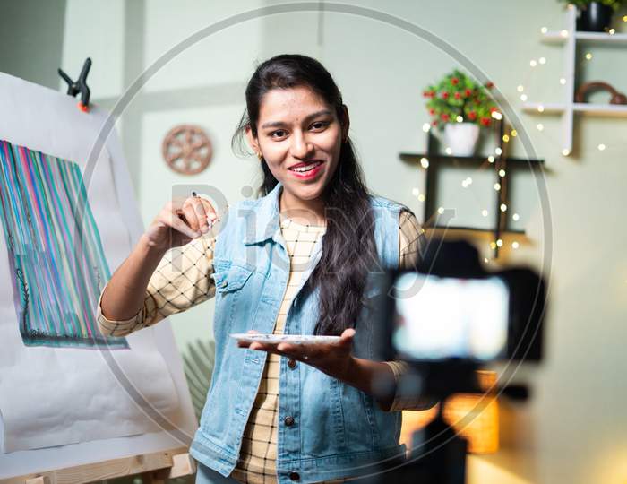 Young girl artist teaching canvas paiting by recording on camera - concept of online teaching, virtual class or education during coronavirus, covid-19 pandemic.