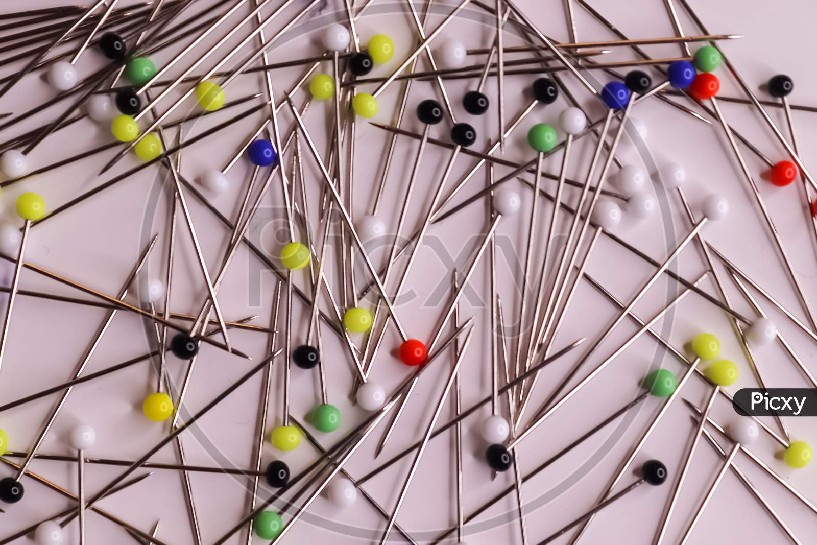Selective Focus Of Many Pins With Coloured Glass Heads On A White Background.