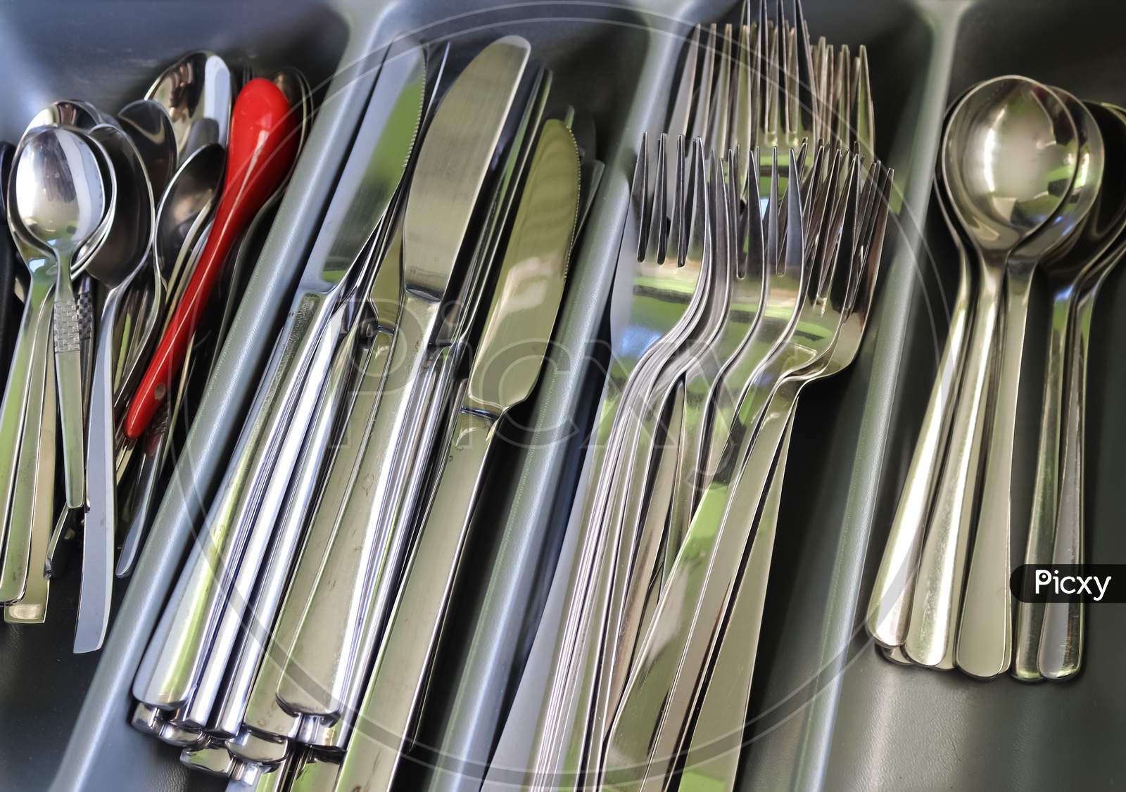 Selective Focus Of Shiny Cutlery In A Dishwasher After Cleaning. Forks, Knifes And Spoons