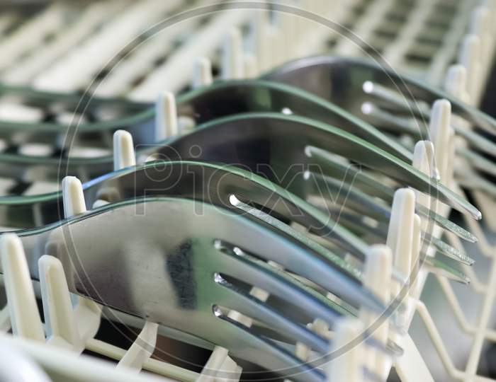 Selective Focus Of Shiny Cutlery In A Dishwasher After Cleaning. Forks, Knifes And Spoons