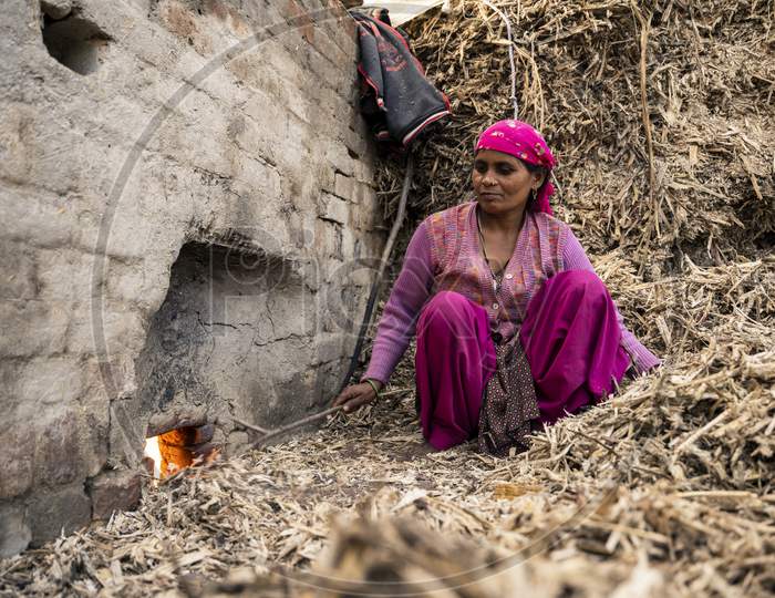 Moradabad, Uttar Pradesh- January 12 2022- A Village Woman Working In The Jaggery Making Factory. Woman Working With Waste Sugarcane.