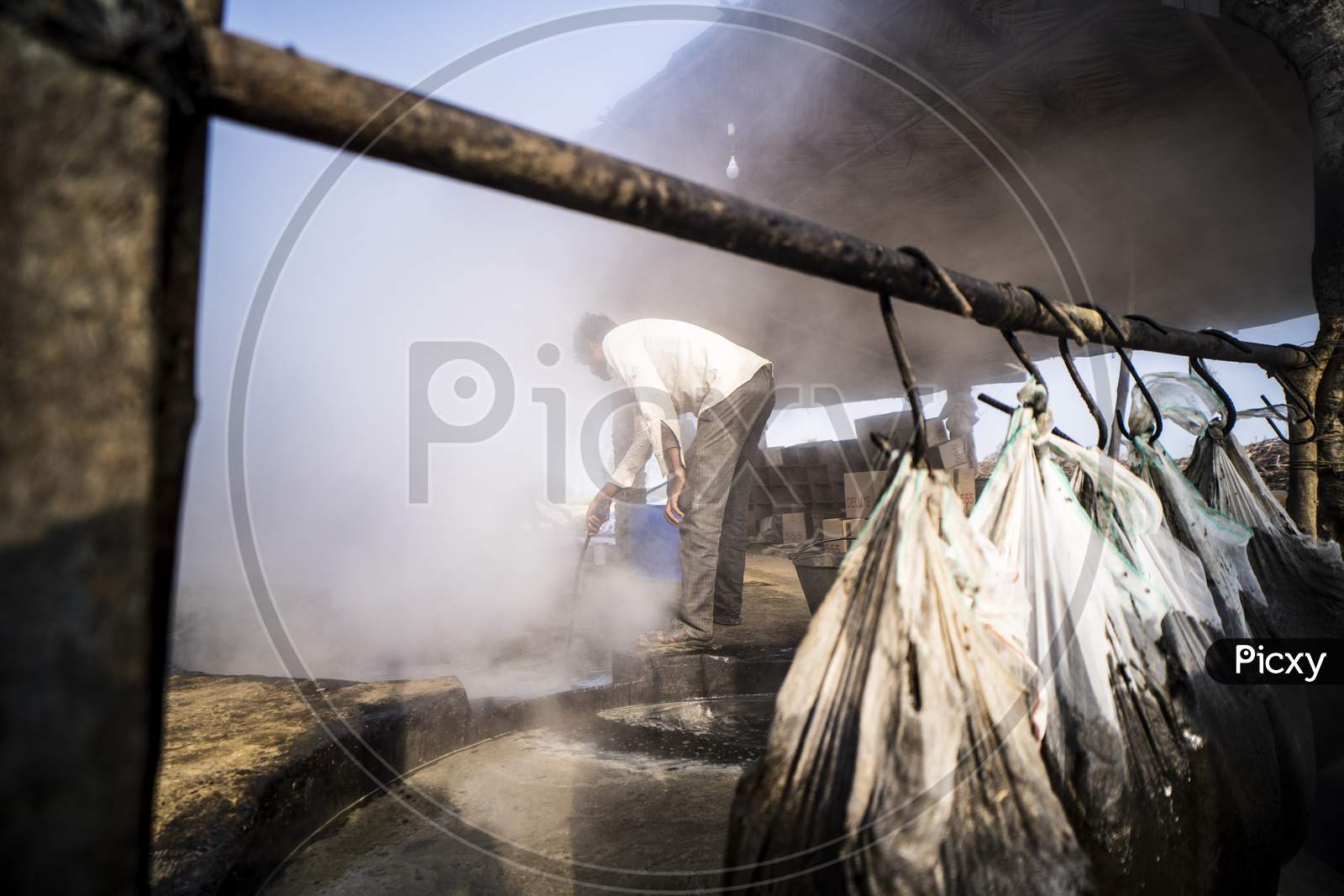 Delhi, India- January 12 2022- Indian Men Making Jaggery, Jaggery Traditional Non-Centrifugal Sugar Consumed In India. Man Cleaning Sugarcane Water.