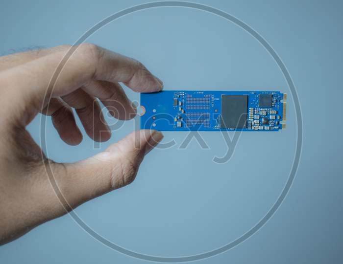 Man hand holding NVME PCIE SSD hard drive disk having high read and write speed memory.Grey Background.