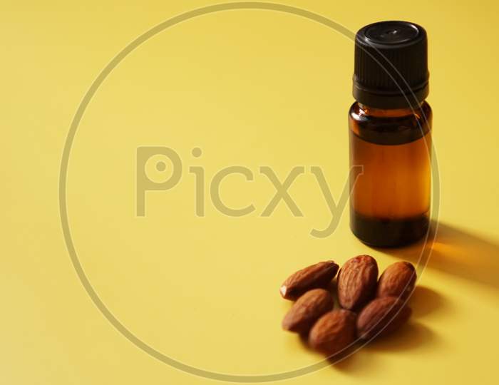 Bottle Of Almond Oil And Almonds On Yellow Background