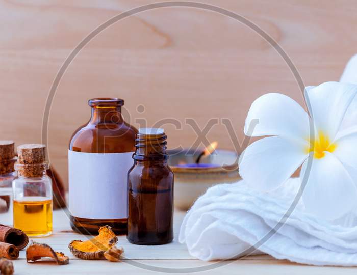 Natural Spa Ingredients And Bottle Of Herbal Extract Oil For Alternative Medicine And Aromatherapy. Thai Spa Theme With Ayurvedic Therapist On Shabby Wooden Background.