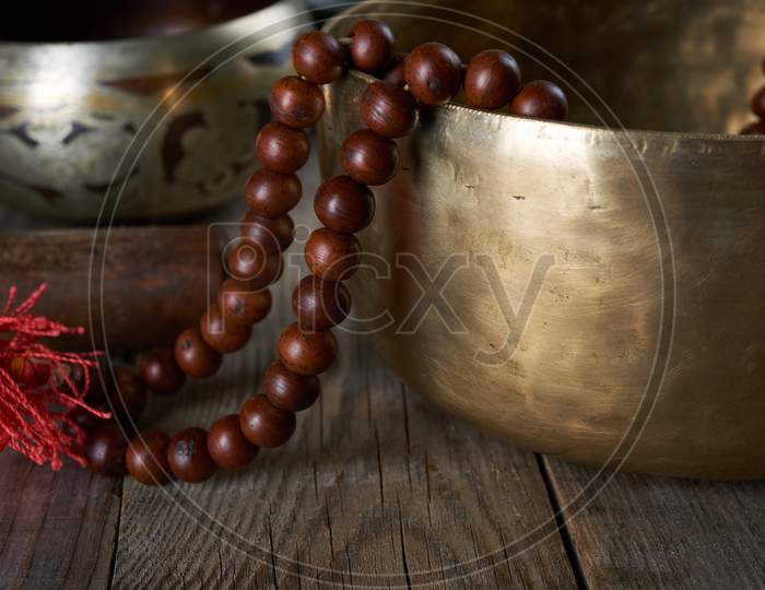 Tibetan Singing Copper Bowl With A Wooden Clapper And Prayer Rosary On A Gray Wooden Table