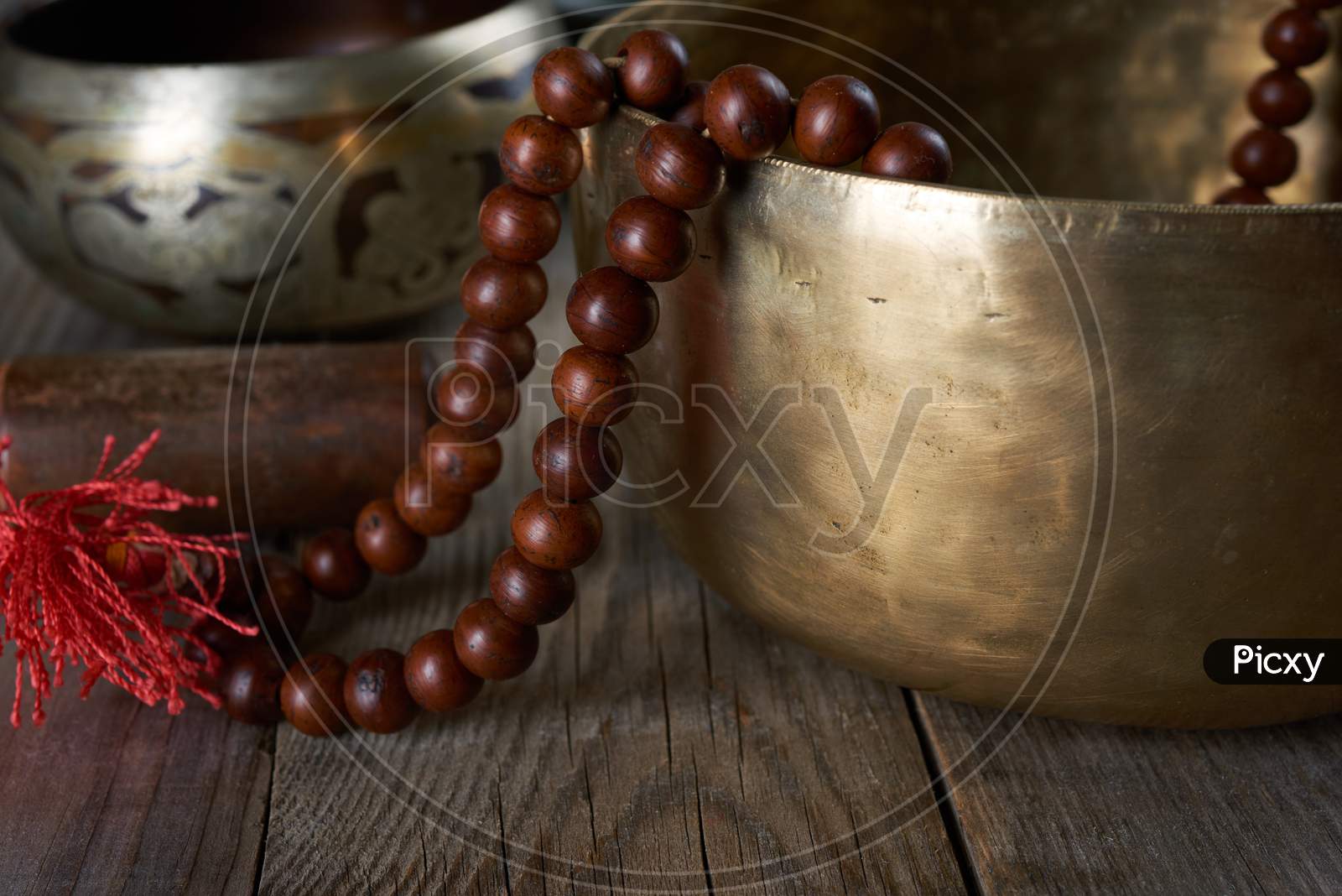 Tibetan Singing Copper Bowl With A Wooden Clapper And Prayer Rosary On A Gray Wooden Table