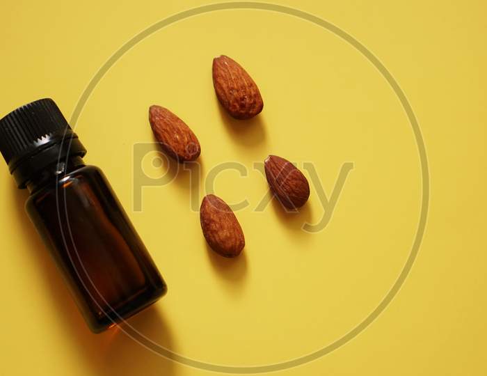 Bottle Of Almond Oil And Almonds On Yellow Background