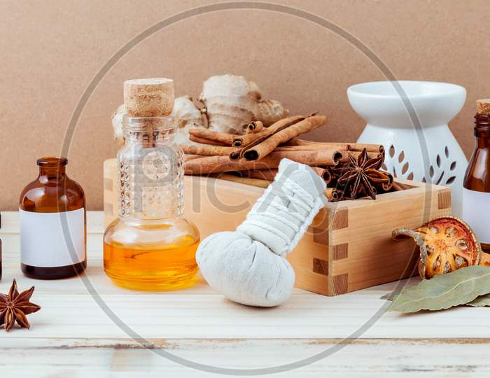 Bottle Of Essential Oil For Ayurveda Massage With Cinnamon Stick ,Star Anise ,Bay Leaves Ginger Root And Herbal Compress Ball With Selective Focus On Shabby Wooden Background .