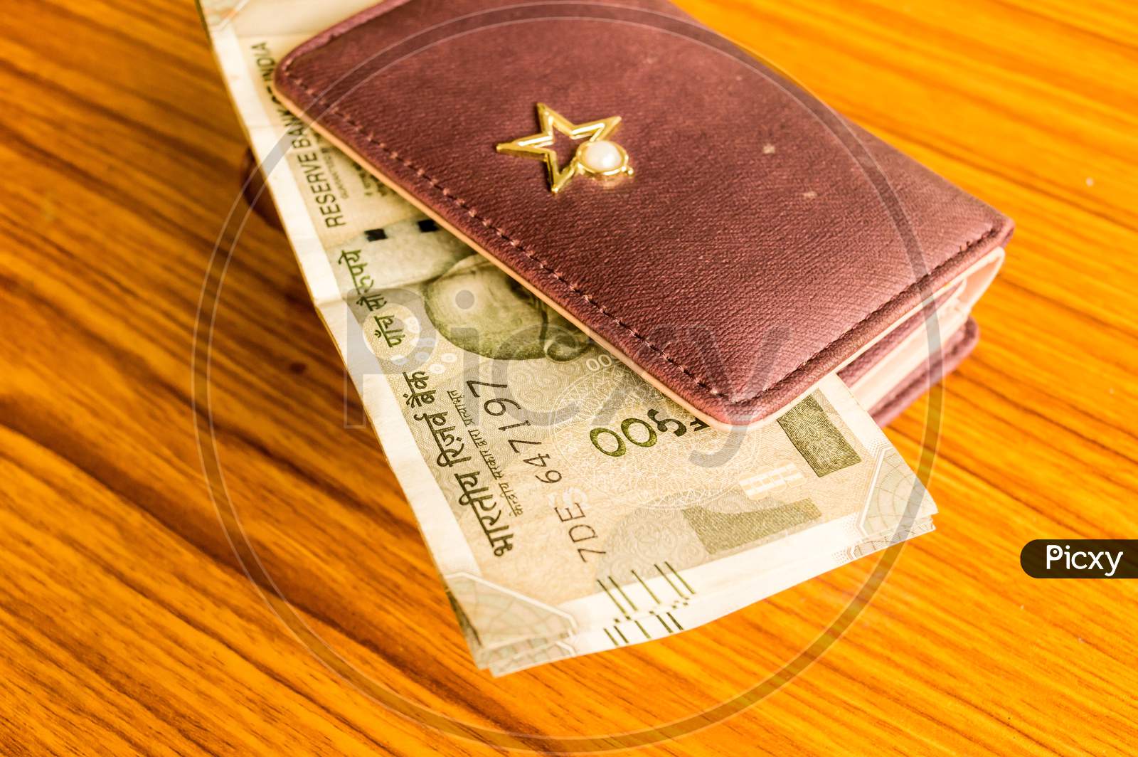 Indian Five Hundred (500) Rupee Cash Note In Brown Color Wallet Leather Purse On A Wooden Table. Business Finance Economy Concept. Side Angel View With Copy Space Room For Text On Left Side Of Image.