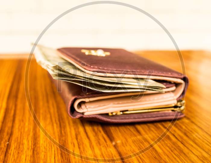 Indian Five Hundred (500) Rupee Cash Note In Brown Color Wallet Leather Purse On A Wooden Table. Business Finance Economy Concept. Side Angel View Extreme Close Up With Copy Space Room For Text Left.