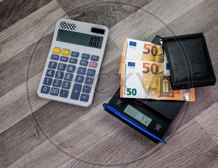 Euro Banknotes On Top Of A Scale With Nearby Calculator