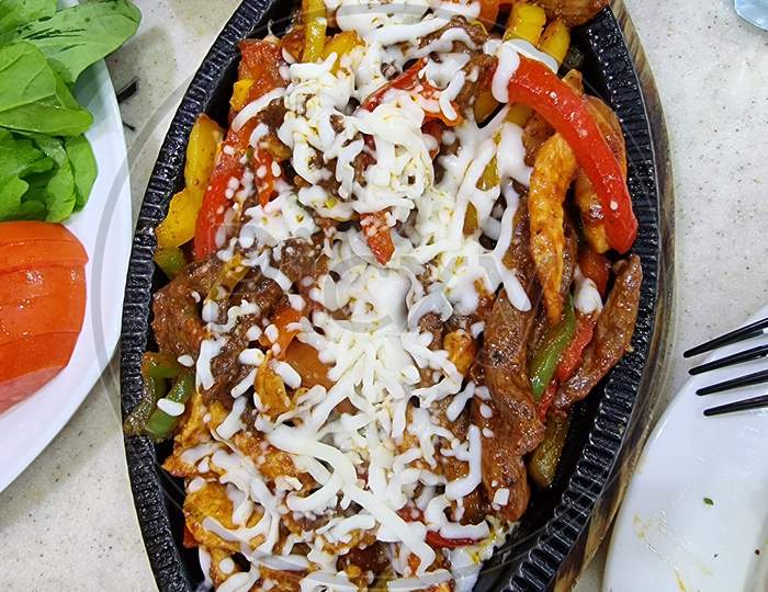 A fajita, in Tex-Mex cuisine, is any stripped grilled meat with stripped peppers and onions that is usually served on a flour or corn tortilla