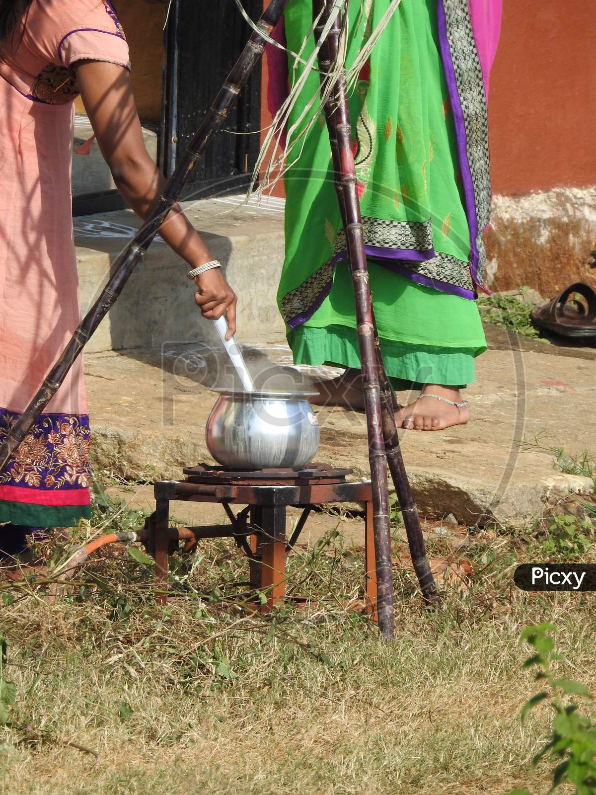 Closeup Of Indian Cute Family Celebrating Makara Sankranti Festival And Making Of Pongal Outside The House.