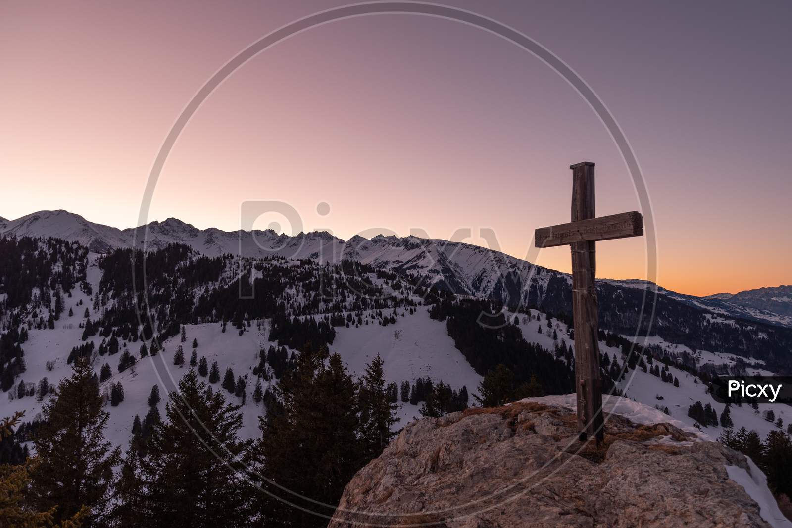 Landquart, Switzerland, December 19, 2021 Holy Cross On The Peak Of The Mount Pizalun In The Evening