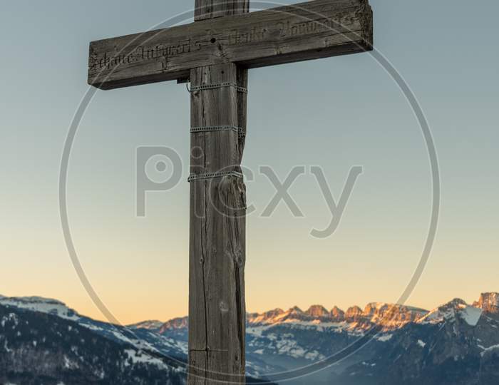 Landquart, Switzerland, December 19, 2021 Holy Cross On The Peak Of The Mount Pizalun In The Evening