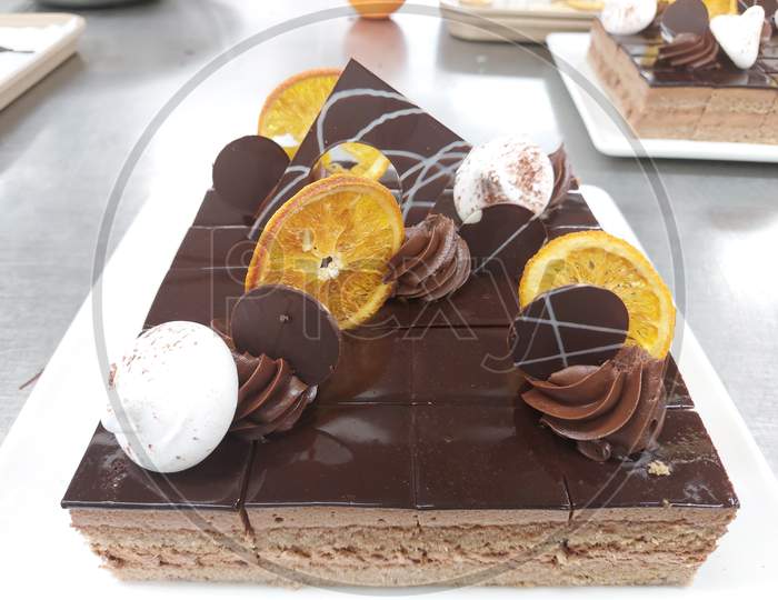 Chocolate Cake On A Plate Garnished With Candied Orange And Meringue