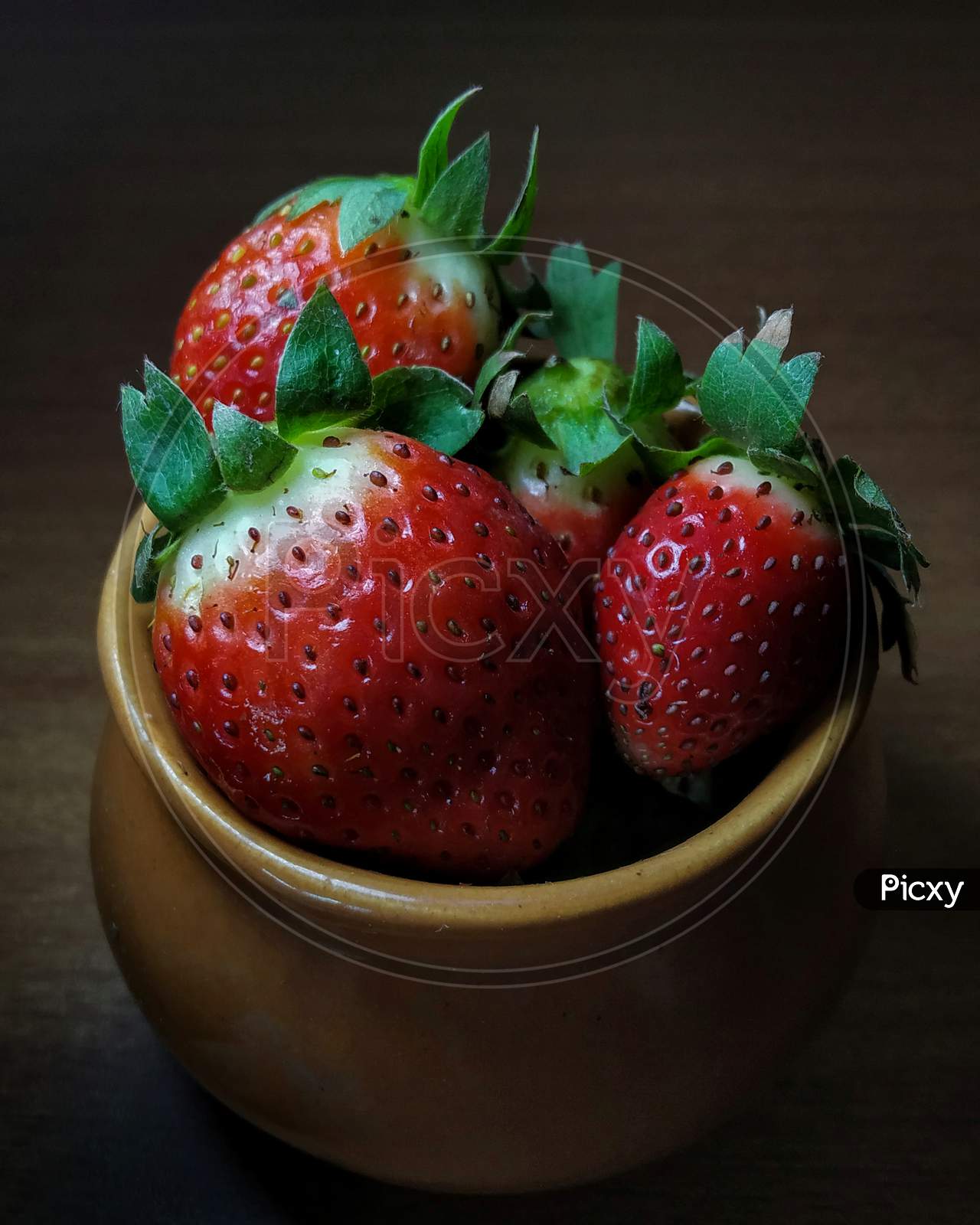 Fresh strawberries in clay pot