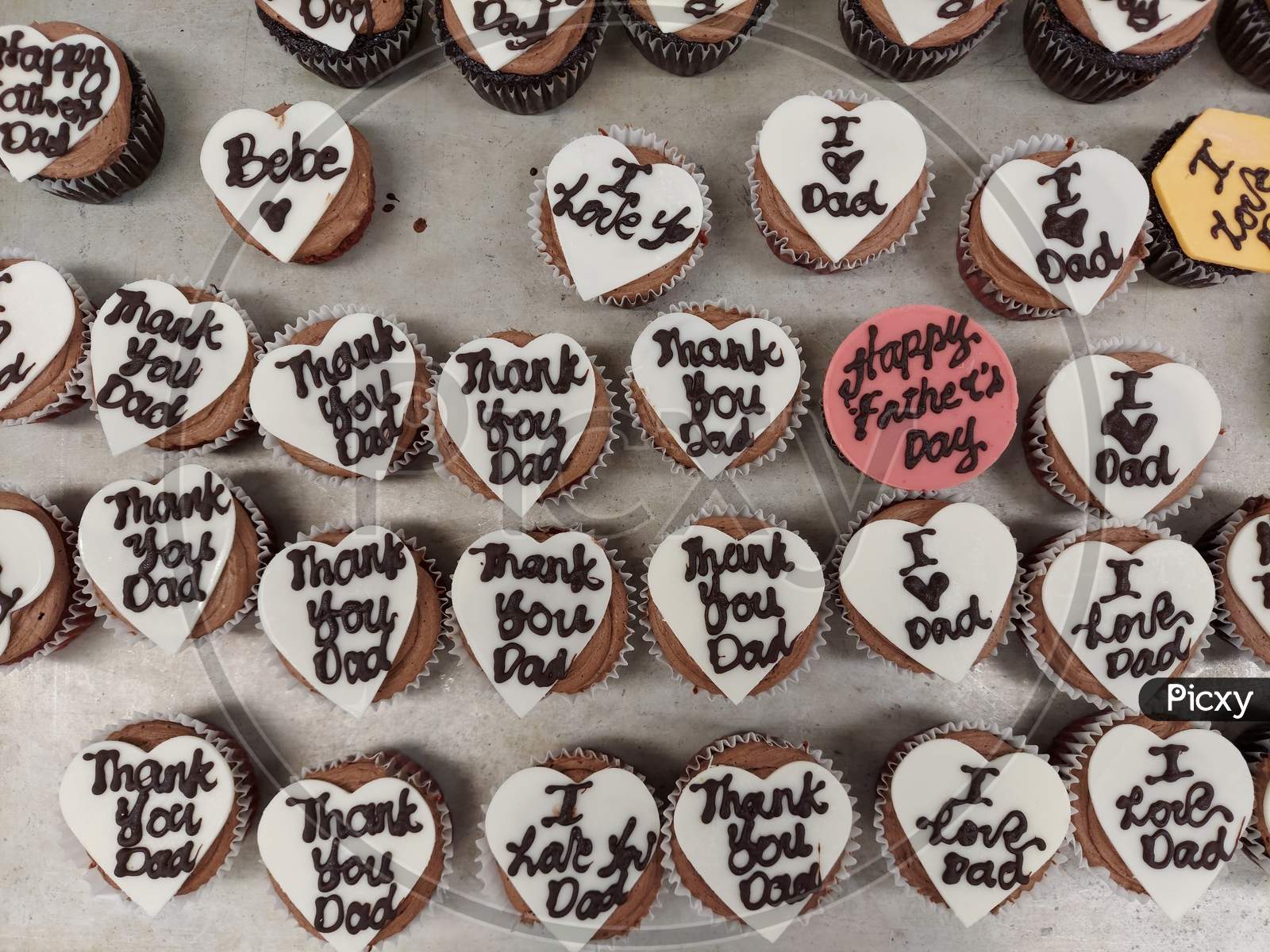 I Love Dad And Thank You Dad Writing On A White Colour Heart Shaped Chocolate Decoration On Top Of A Cupcake