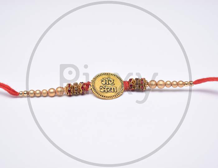 Closeup Shot Of Rakhi With Bhai (Brother) Written On It And Decorated With Beads And Red Thread On White Background