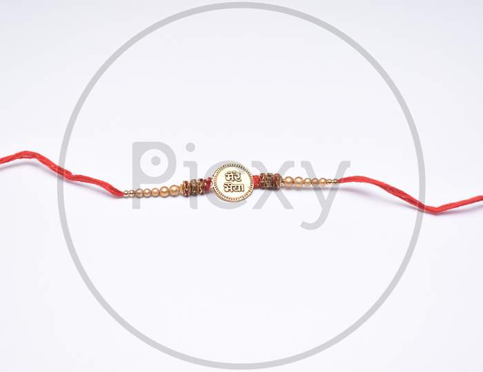 Rakhi With Bhai (Brother) Written On It And Decorated With Beads And Red Thread On White Background
