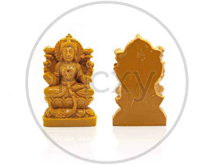 The Statue Of Mahalakshmi Carved In Brown Wood Is Isolated With A White Background With Reflection On The Front And Back.
